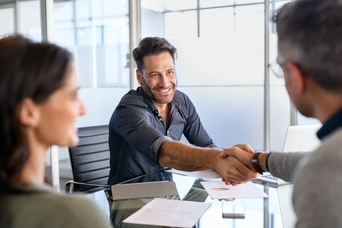 A dealership owner shaking hands across a desk